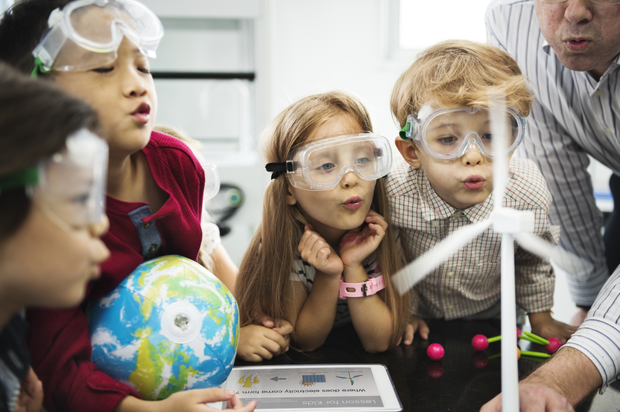 Group of children wearing lab goggles admiring a science experiment.