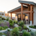 Modern home featuring sustainable design with a landscaped garden, enhanced by construction logos on the visible signage.